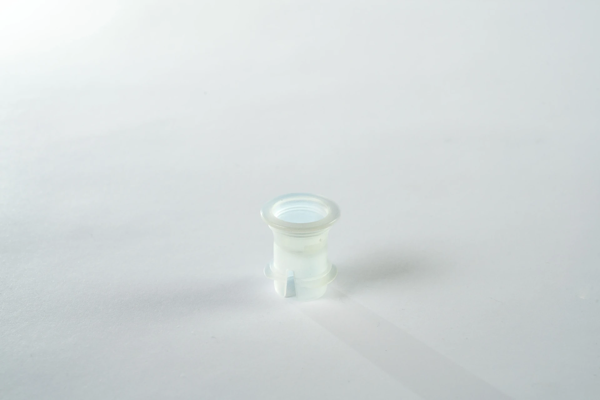 Inserto in plastica traslucida per il collo del flacone, ripreso da vicino su fondo bianco