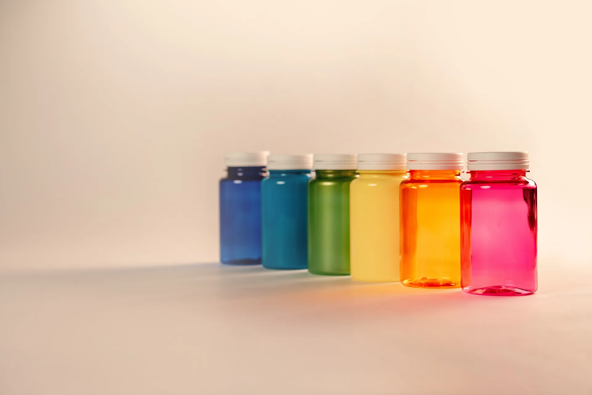 Vasi in PET colorati Ho.Bag - blu, verde, giallo, arancio e rosa - allineati su fondo pesca